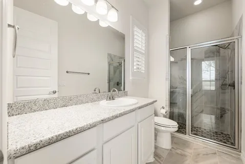 a bathroom with a granite countertop sink a toilet and shower