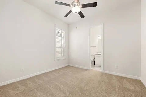 an empty room with chandelier fan and windows