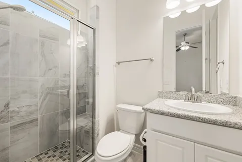 a bathroom with a granite countertop sink a toilet a mirror and shower
