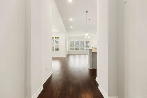 a view of a hallway with wooden floor and a kitchen
