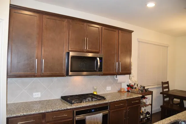 a kitchen with stainless steel appliances wooden cabinets and a stove top oven