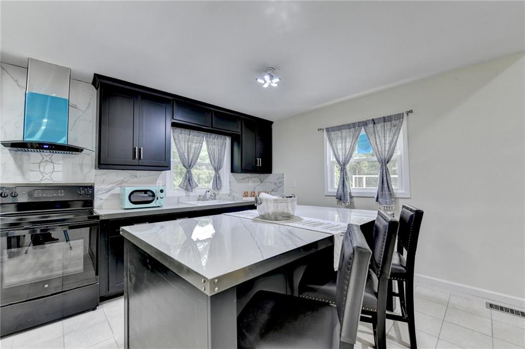 6654 Covington Road Lithonia, GA 30058 - Photo 12 of 39 a kitchen with stainless steel appliances granite countertop a kitchen island a stove a table and chairs