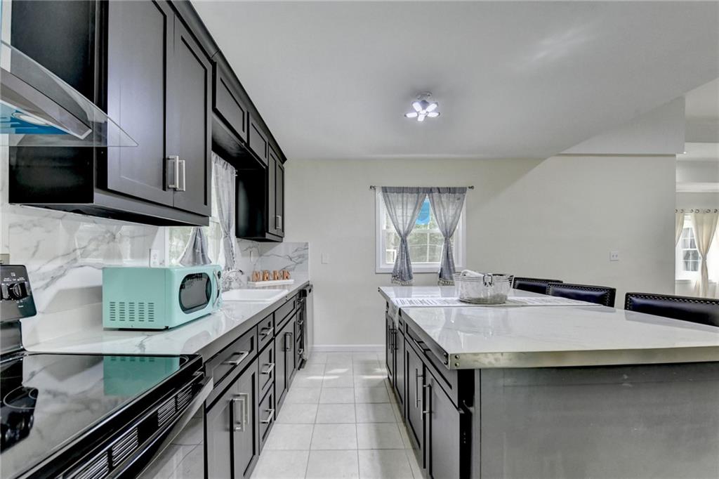 6654 Covington Road Lithonia, GA 30058 - Photo 14 of 39 a kitchen with stainless steel appliances granite countertop a sink a stove and a microwave