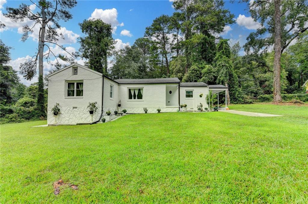 6654 Covington Road Lithonia, GA 30058 - Photo 2 of 39 a white house that has a big yard with wooden fence