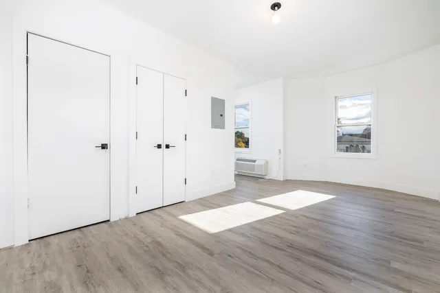an empty room with wooden floor and windows