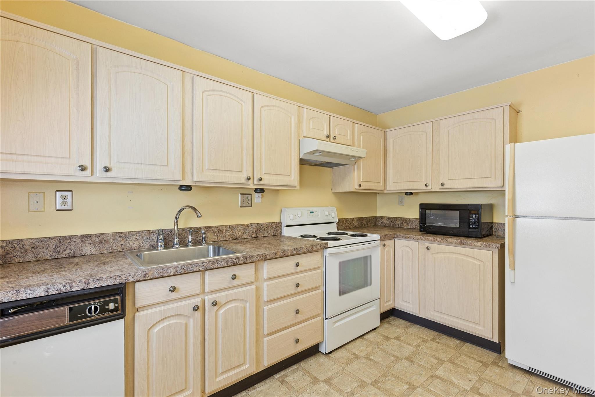 8 Coventry Court Ridge, NY 11961 - Photo 6 of 21 a kitchen with granite countertop white cabinets and white appliances