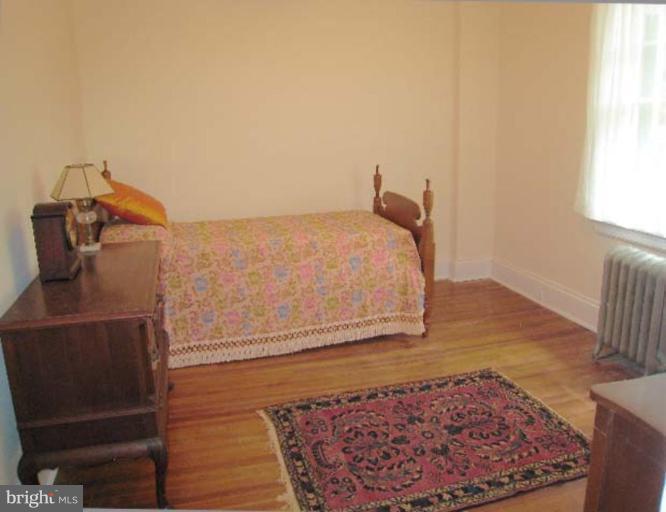 3926 Cloverhill Road Baltimore, MD 21218 - Photo 8 of 24 a bedroom with a bed and wooden floor
