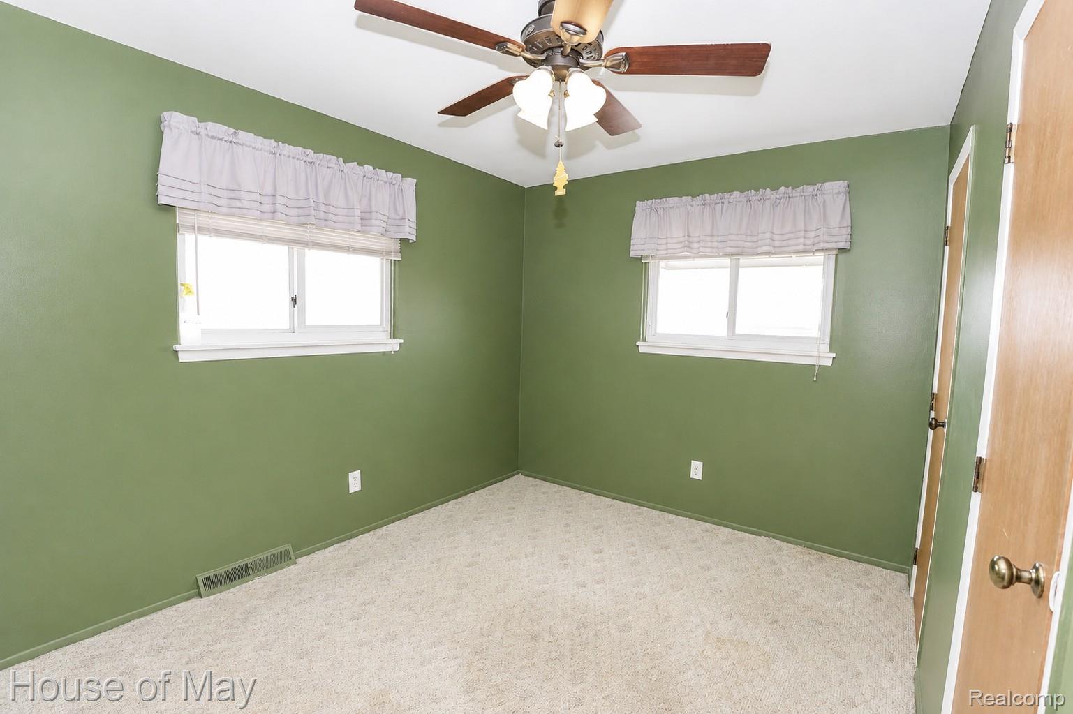 Room featuring two windows, green painted walls, and textured carpet flooring