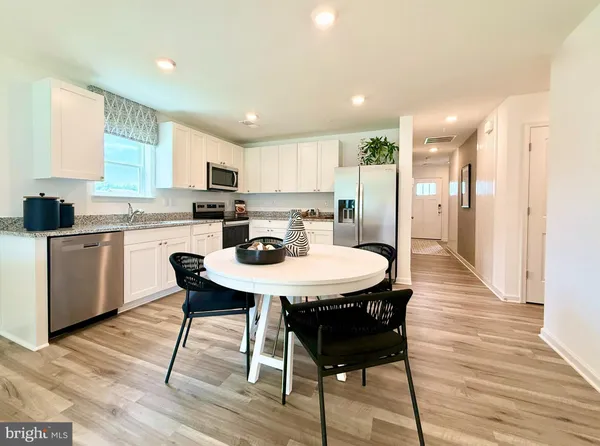 a kitchen with stainless steel appliances kitchen island granite countertop a sink a stove a dining table and chairs