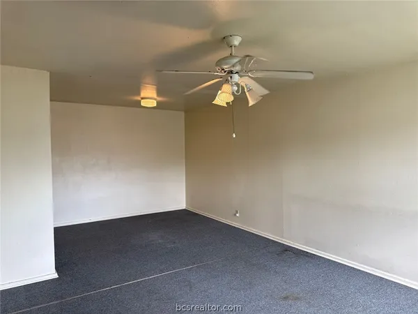 an empty room with a window and a ceiling fan