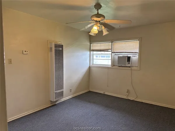 an empty room with chandelier fan and windows