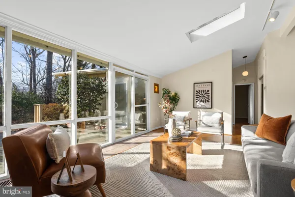 a living room with furniture large windows and wooden floor