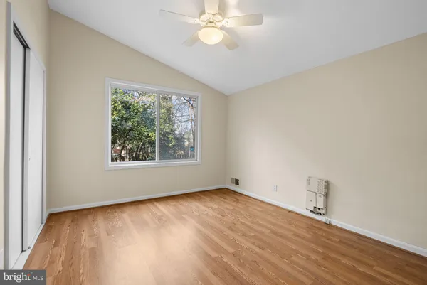 an empty room with wooden floor fan and windows