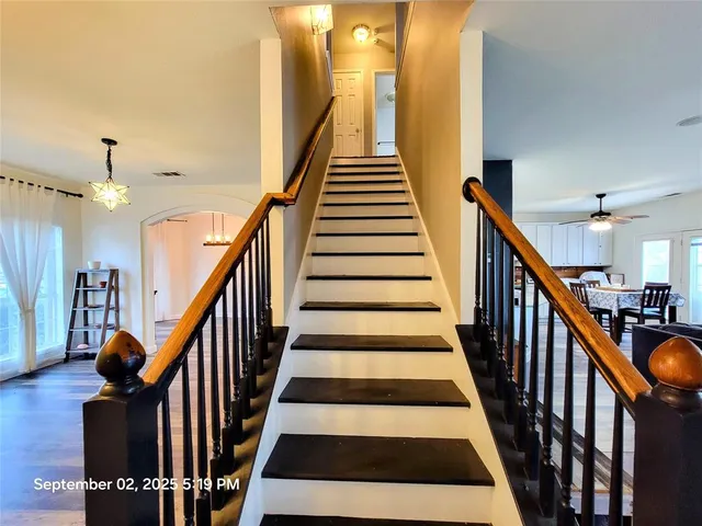 a view of staircase with wooden floor and a chandelier