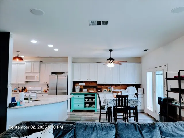 a kitchen with stainless steel appliances a dining table chairs and a refrigerator