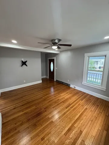 a view of an empty room with wooden floor and a window