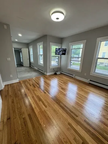 a view of empty room with wooden floor and fan