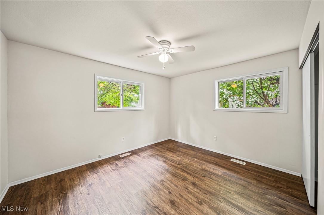 1816 Red Bird Road Madison, OH 44057 - Photo 15 of 24 Empty room with healthy amount of natural light, dark wood finished floors, baseboards, and ceiling fan
