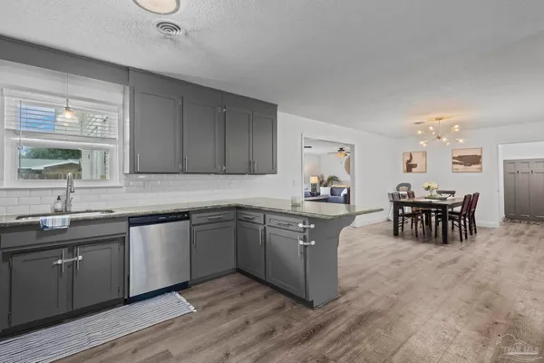 a kitchen with stainless steel appliances granite countertop wooden cabinets a dining table and chairs