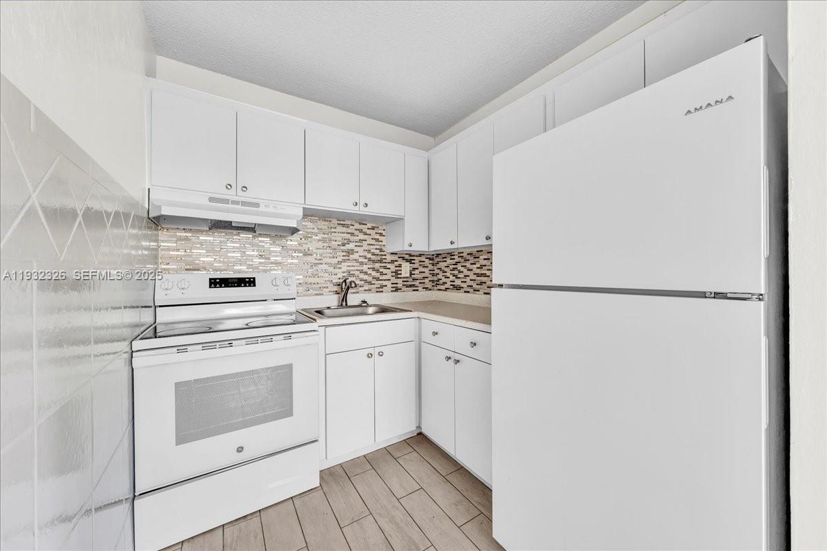 2025 Miami Road, Unit 19 Fort Lauderdale, FL 33316 - Photo 13 of 30 a kitchen with granite countertop white cabinets and white appliances