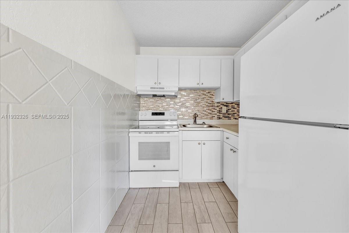 2025 Miami Road, Unit 19 Fort Lauderdale, FL 33316 - Photo 14 of 30 a kitchen with white cabinets and white appliances