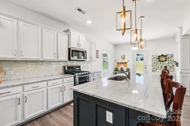 a kitchen with stainless steel appliances granite countertop a sink a stove and cabinets