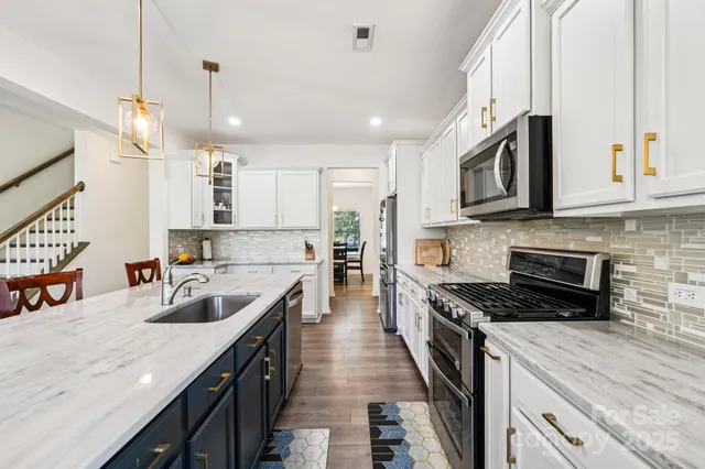 a kitchen with kitchen island granite countertop a sink a counter space stainless steel appliances and cabinets