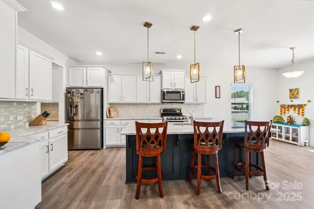 a kitchen with stainless steel appliances kitchen island granite countertop a table chairs and a refrigerator