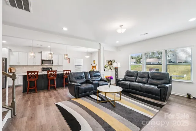 a living room with furniture and a dining table with wooden floor