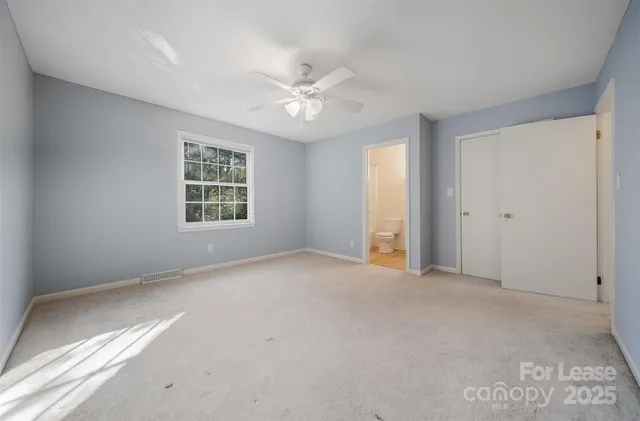 an empty room with windows and ceiling fan