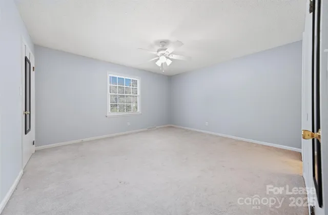 an empty room with windows and ceiling fan