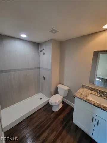 a bathroom with a granite countertop sink a toilet and shower