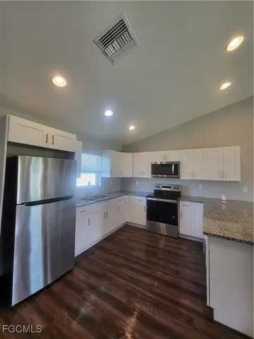 a kitchen with granite countertop a refrigerator and a stove top oven