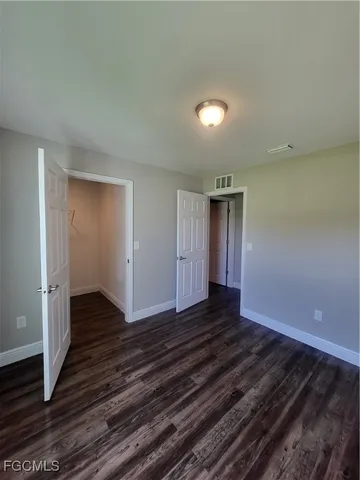 a view of an empty room with wooden floor and closet