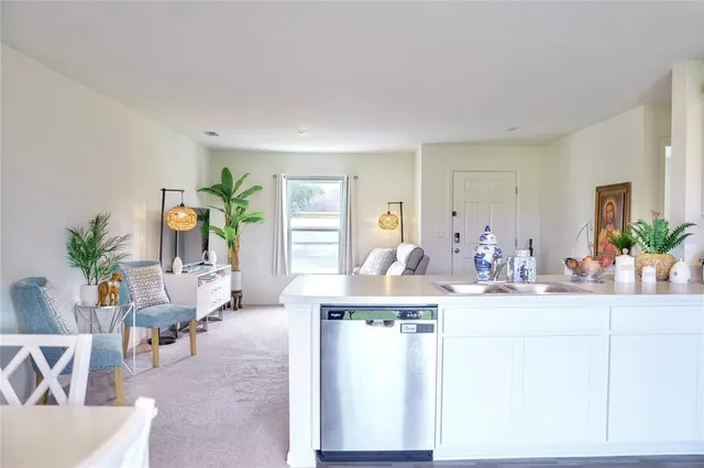 a living room with furniture a potted plant and a kitchen view