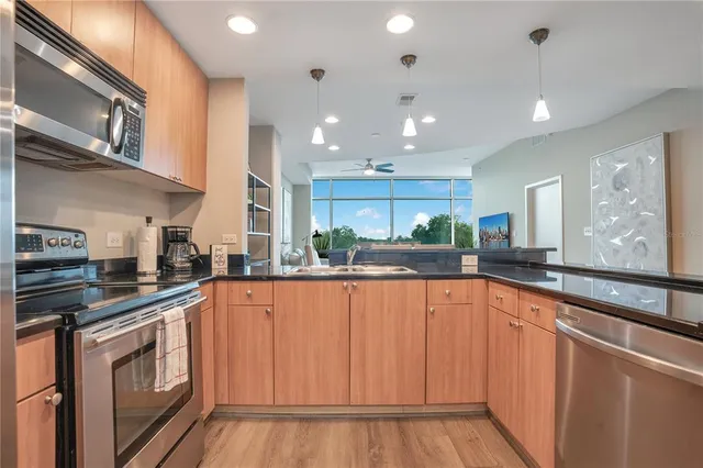 a kitchen view with stainless steel appliances a refrigerator a stove top oven a sink and a center island