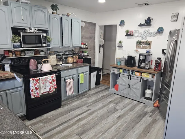 a living room with stainless steel appliances furniture a fireplace and a flat screen tv
