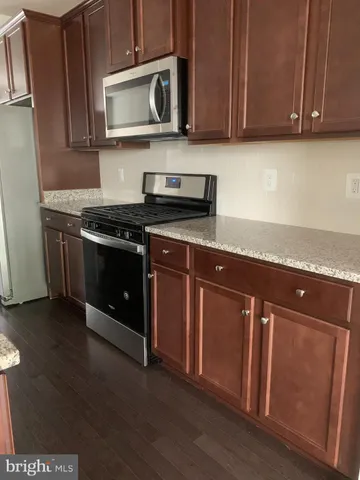 a kitchen with granite countertop a stove a microwave a sink and cabinets