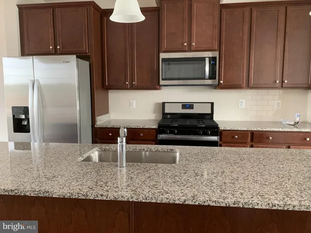 a kitchen with granite countertop a refrigerator oven a sink and dishwasher