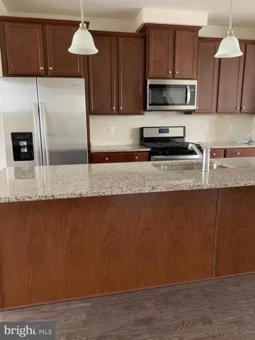 a kitchen with stainless steel appliances granite countertop a sink a microwave a refrigerator and cabinets