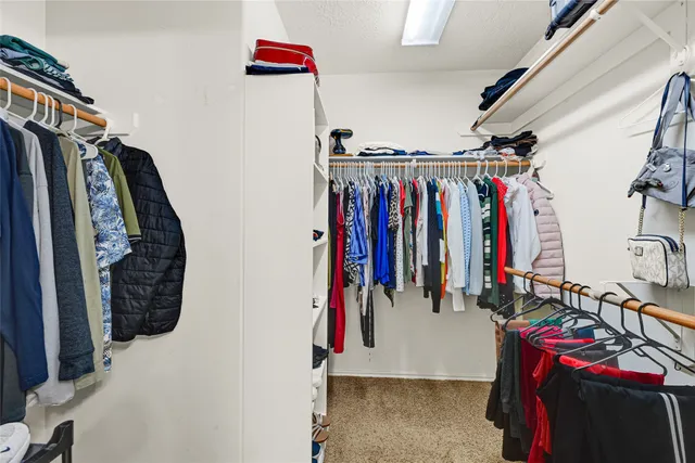 a view of walk in closet with clothes and shoes