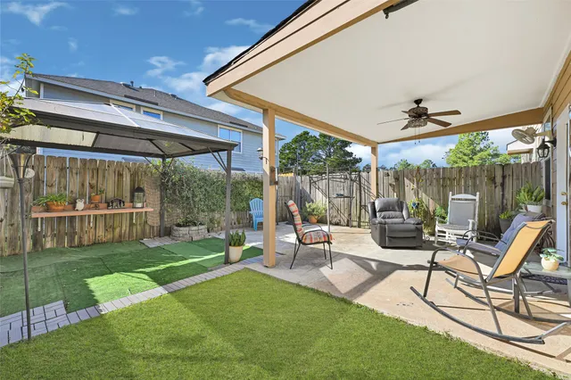 a view of a patio with table and chairs under an umbrella next to a yard