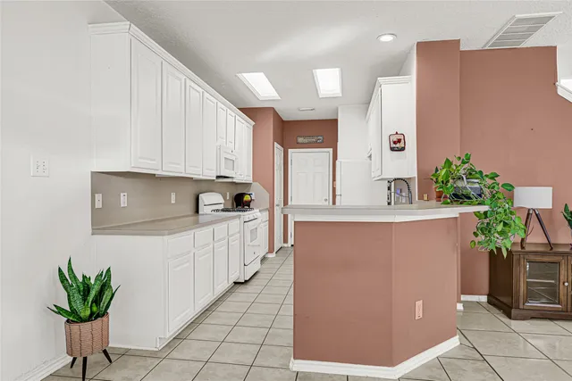a kitchen with granite countertop a refrigerator a stove and white cabinets