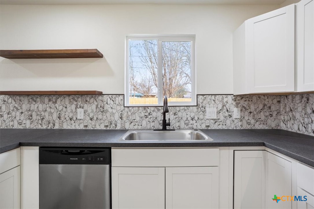 707 South 13th Street Temple, TX 76504 - Photo 12 of 24 a kitchen with granite countertop white cabinets and a window