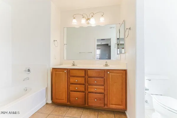 a spacious bathroom with a double vanity sink a mirror a bathtub and a toilet