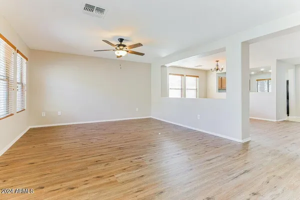 an empty room with wooden floor fan and windows