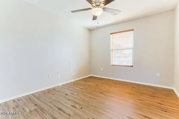 an empty room with wooden floor fan and windows