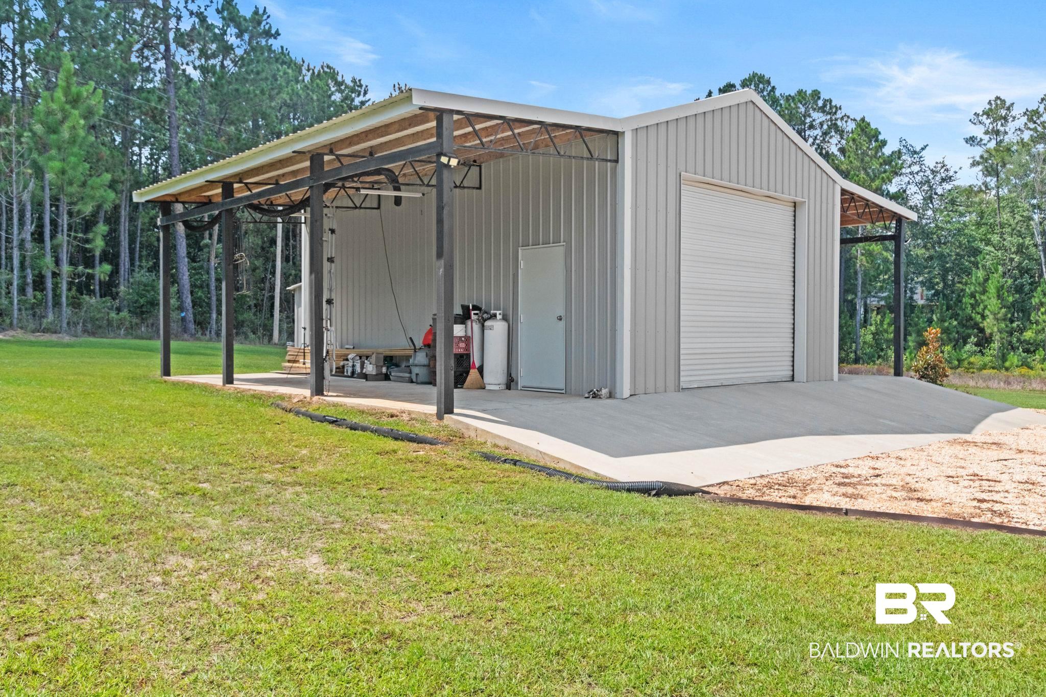 79 Whitetail Run Chatom, AL 36518 - Photo 74 of 82 Metal workshop building featuring a roll-up door, side entry door, and an extended covered awning