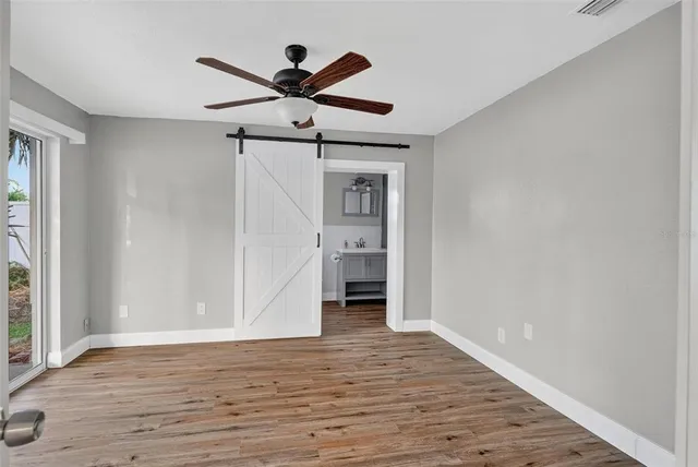 a view of empty room with wooden floor and ceiling fan