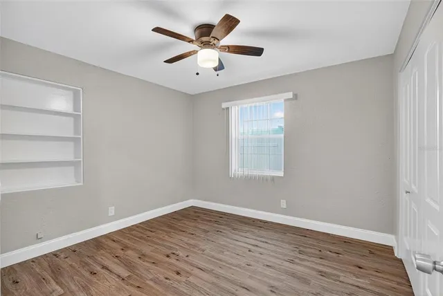 a view of empty room with wooden floor and fan